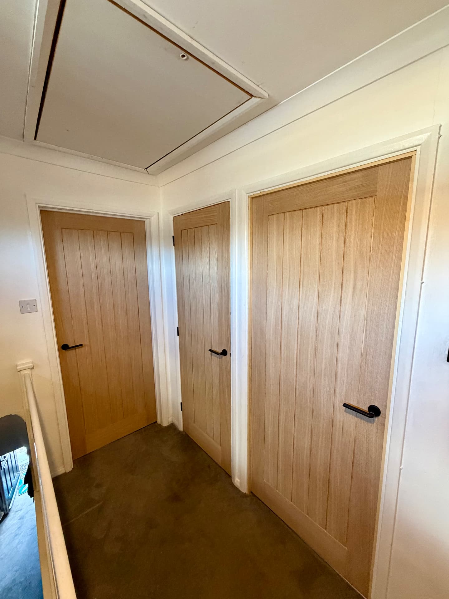 Light oak slatted cottage doors with matte black levers fitted along an upstairs landing
