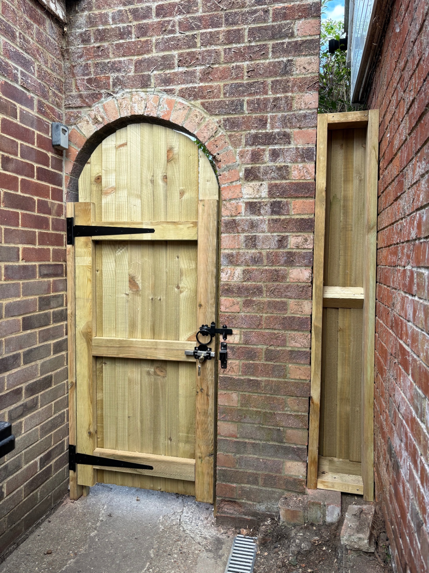 Bespoke arched timber side gate with black iron hinges and keyed deadlock