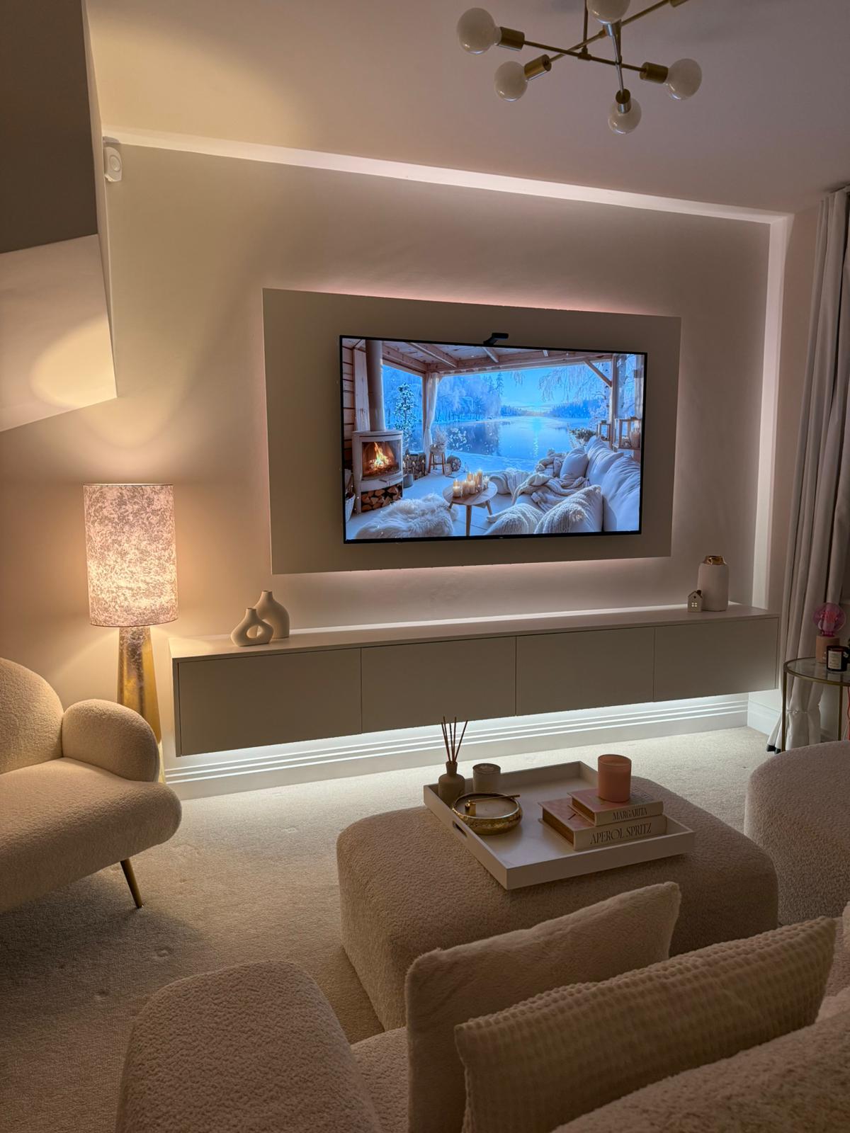 Snug media wall with floating cabinet, warm LED backlit TV panel and floor uplighting