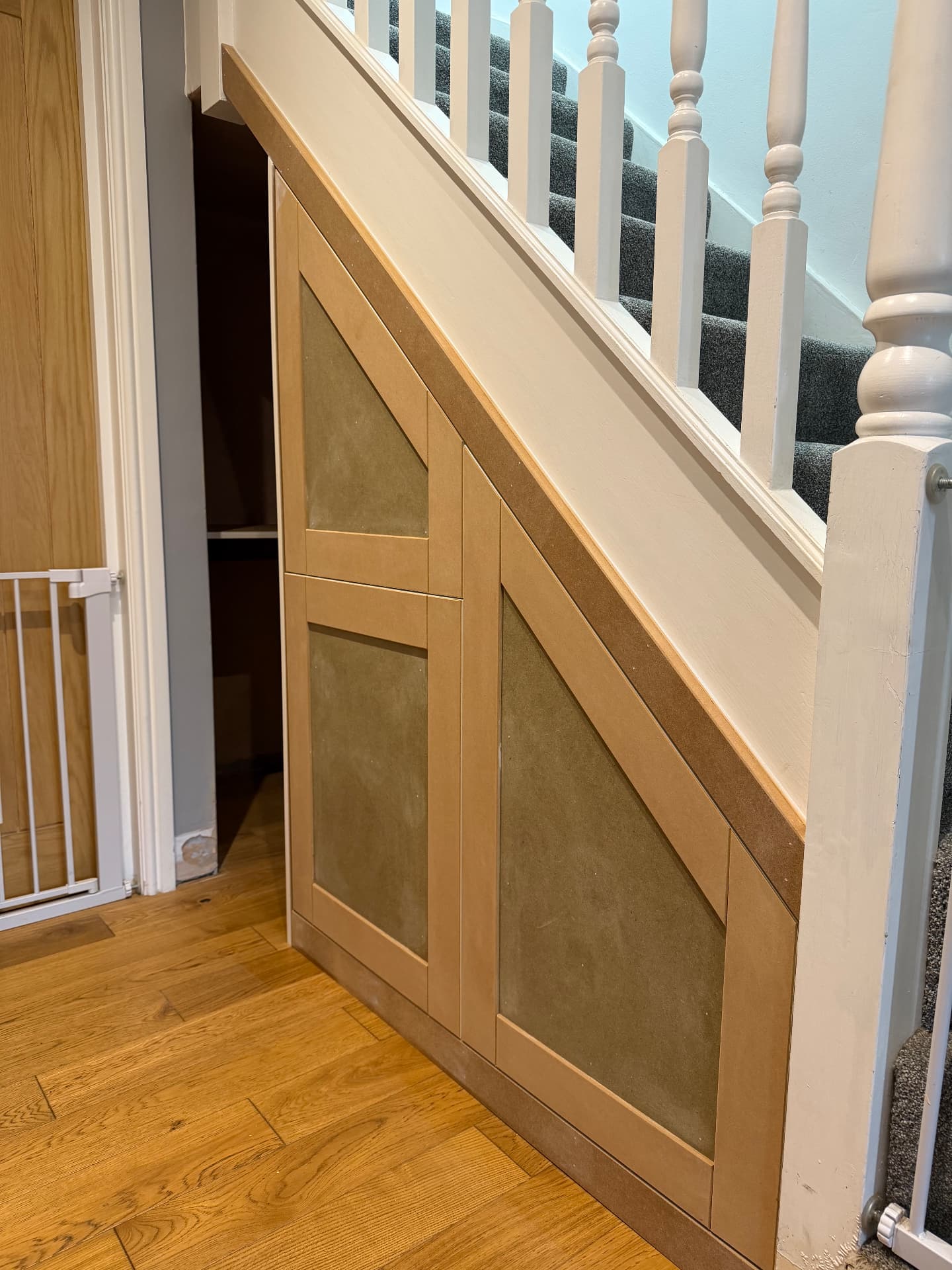 Understairs storage with angled shaker doors under a white staircase
