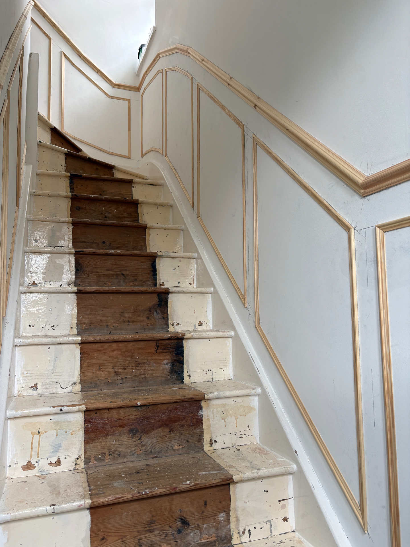 Unpainted staircase panelling with custom mouldings fitted along the stairs