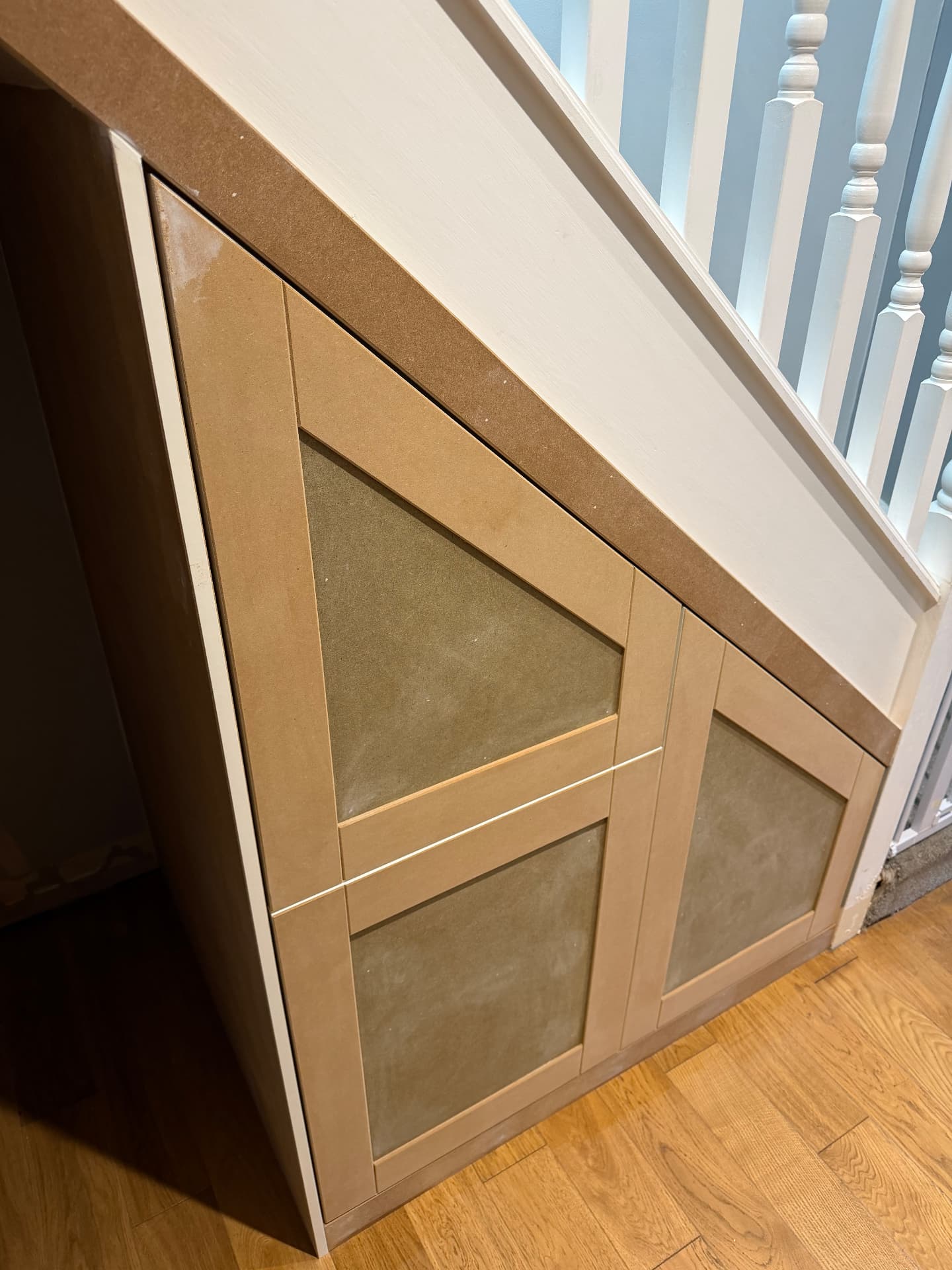 Shaker-style understairs storage doors shaped to the staircase