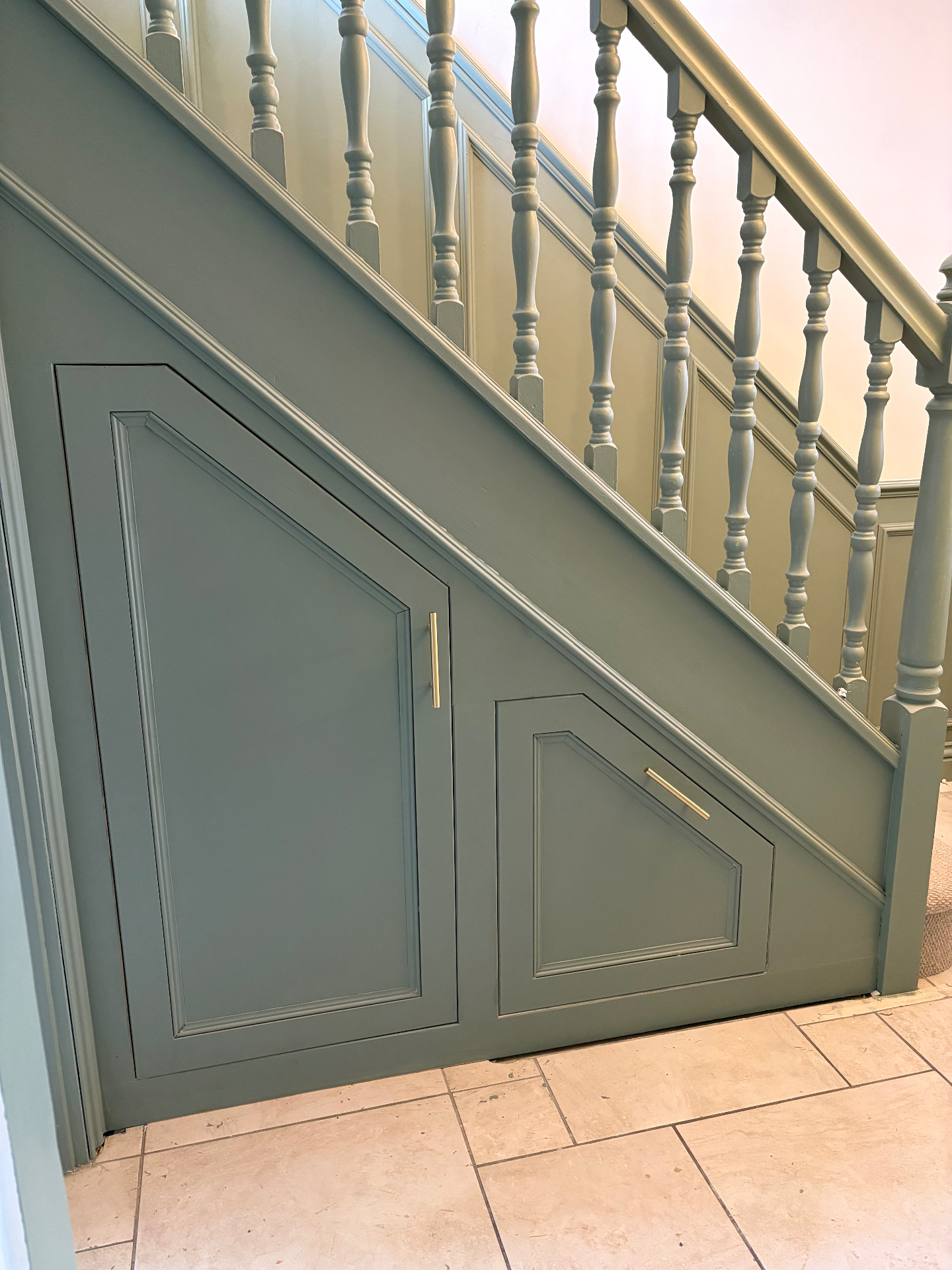 Bespoke understairs storage cupboards in sage green with brass bar handles