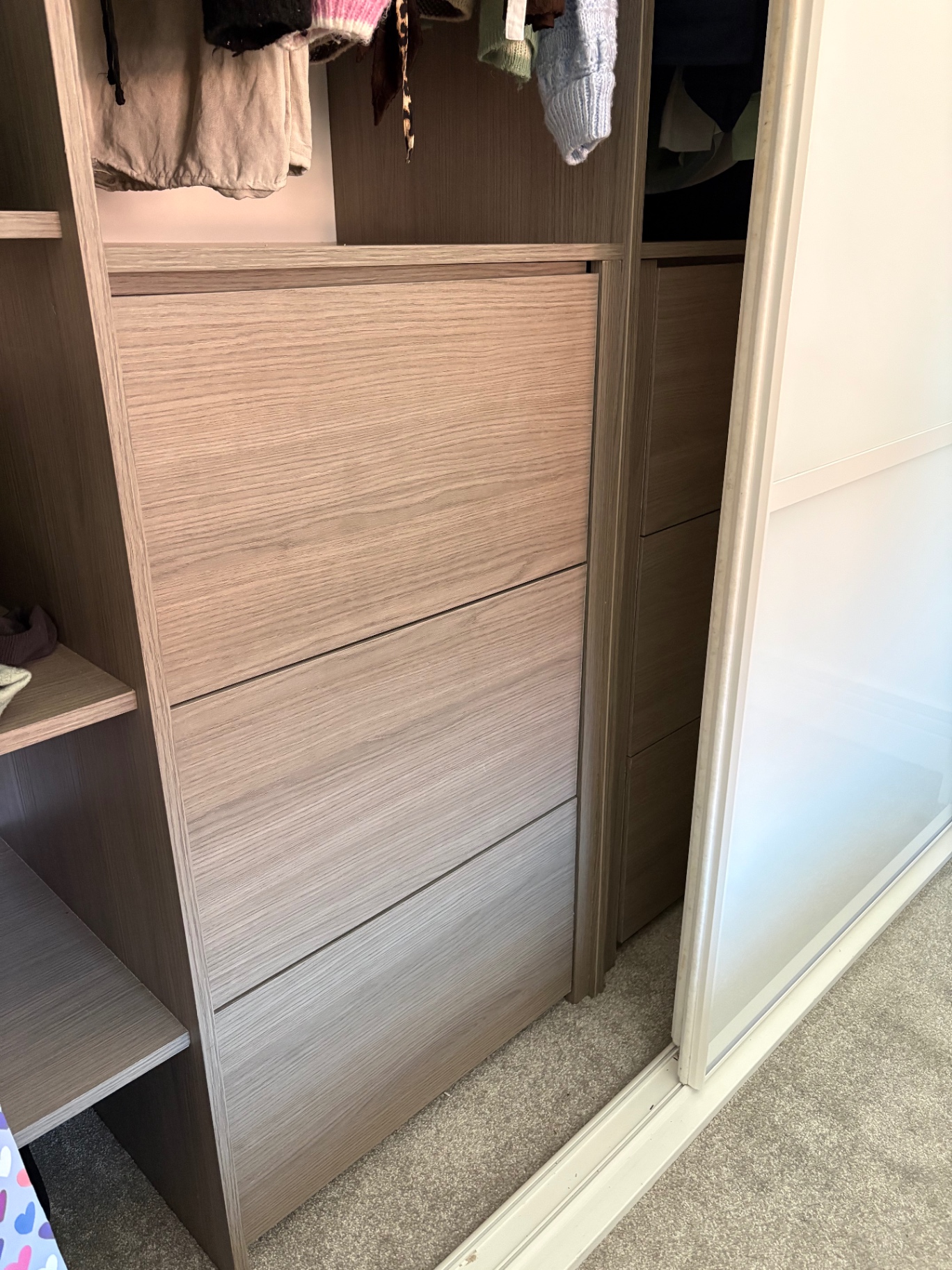 Bespoke fitted wardrobe interior with oak-effect drawer bank and hanging space