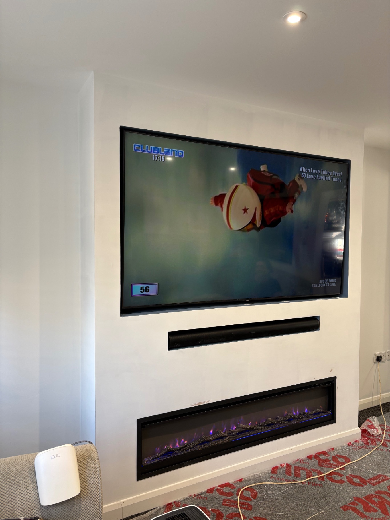 White media wall with wall-mounted TV, recessed soundbar and inset electric fireplace