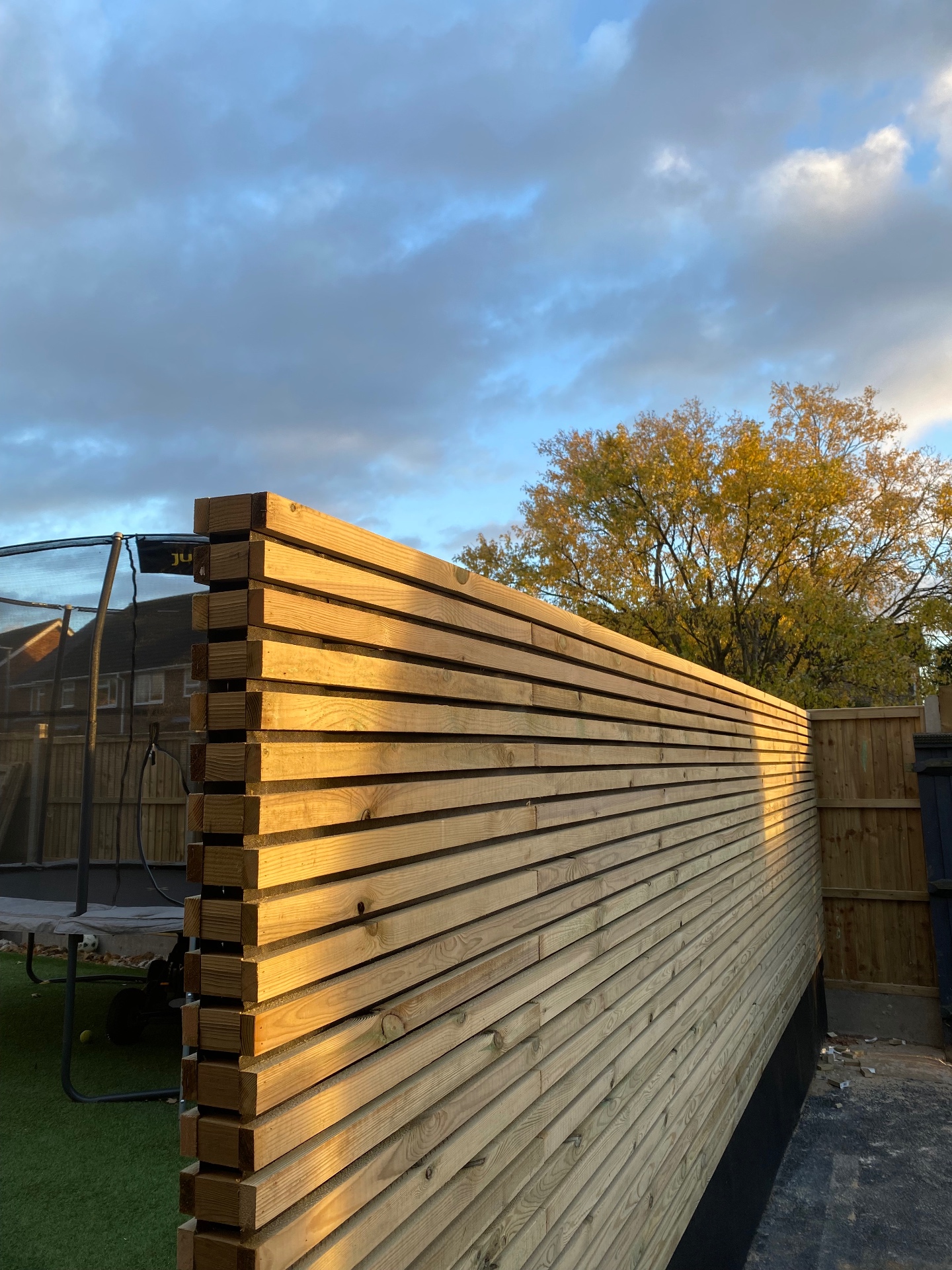 Contemporary horizontal timber slat privacy screen glowing in low evening sun