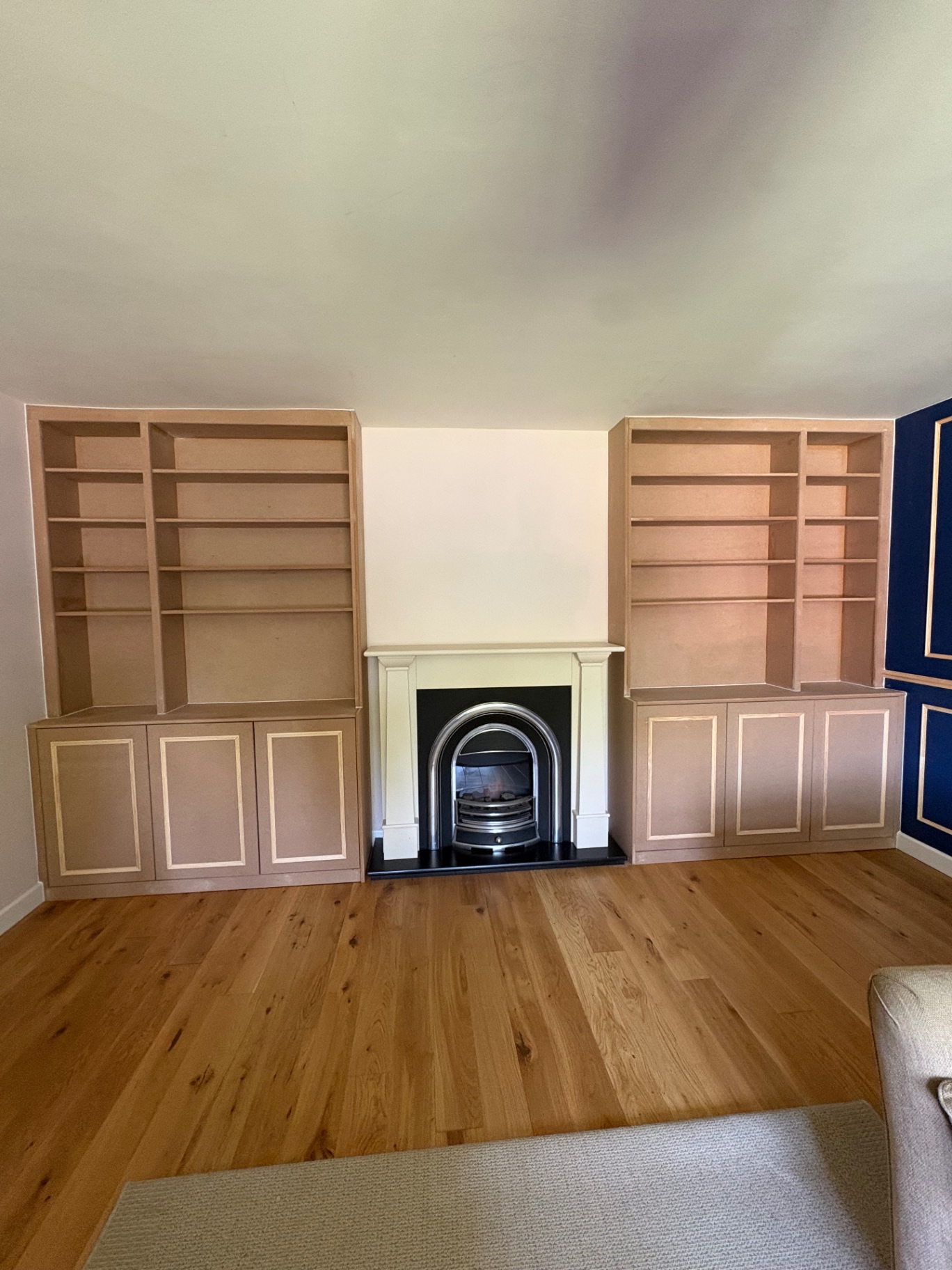 Pair of bespoke alcove bookcases with base cupboards flanking a fireplace, ready for paint