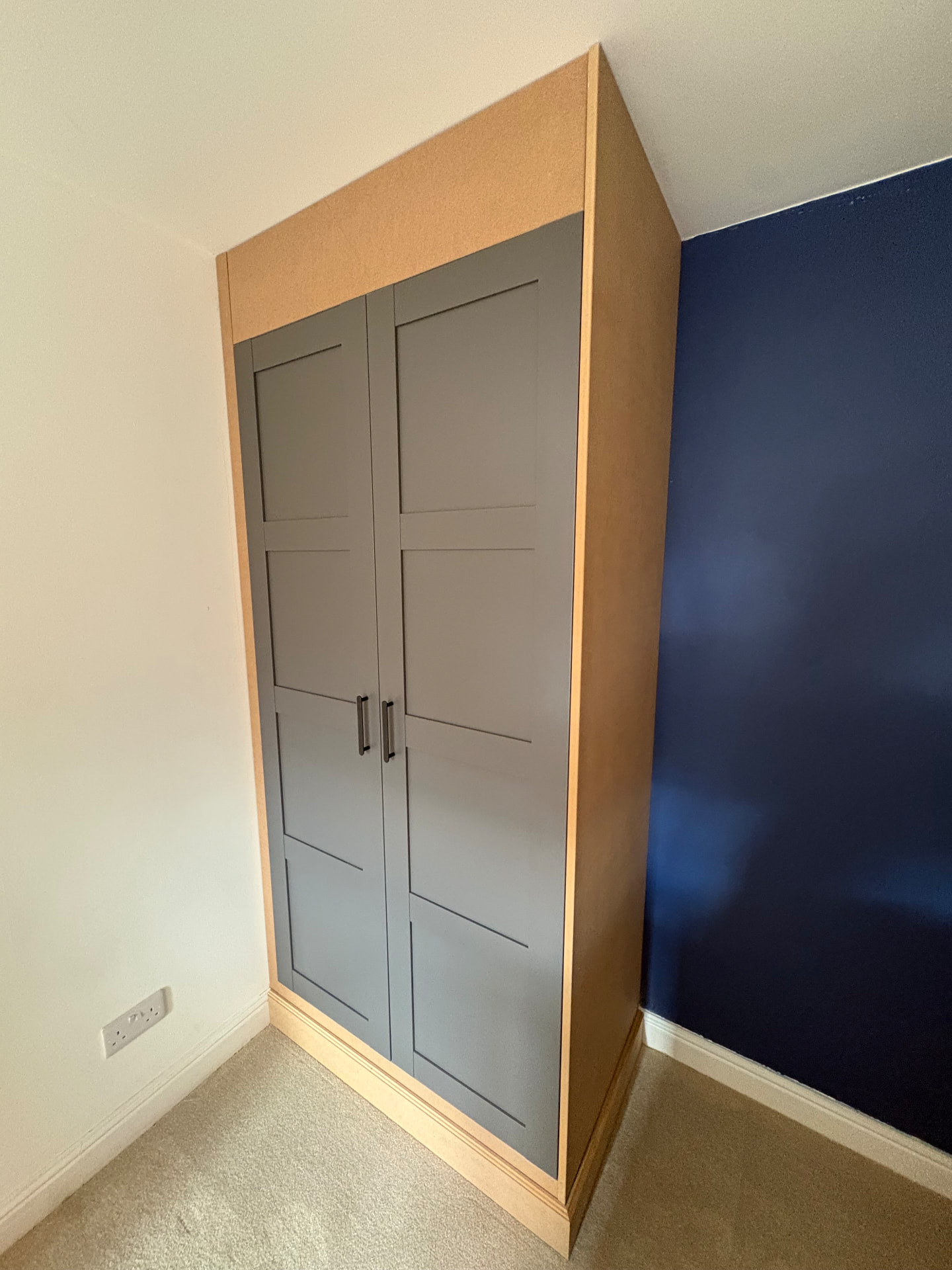 Two-door charcoal shaker fitted wardrobe with slim black bar handles, surrounding joinery still raw MDF