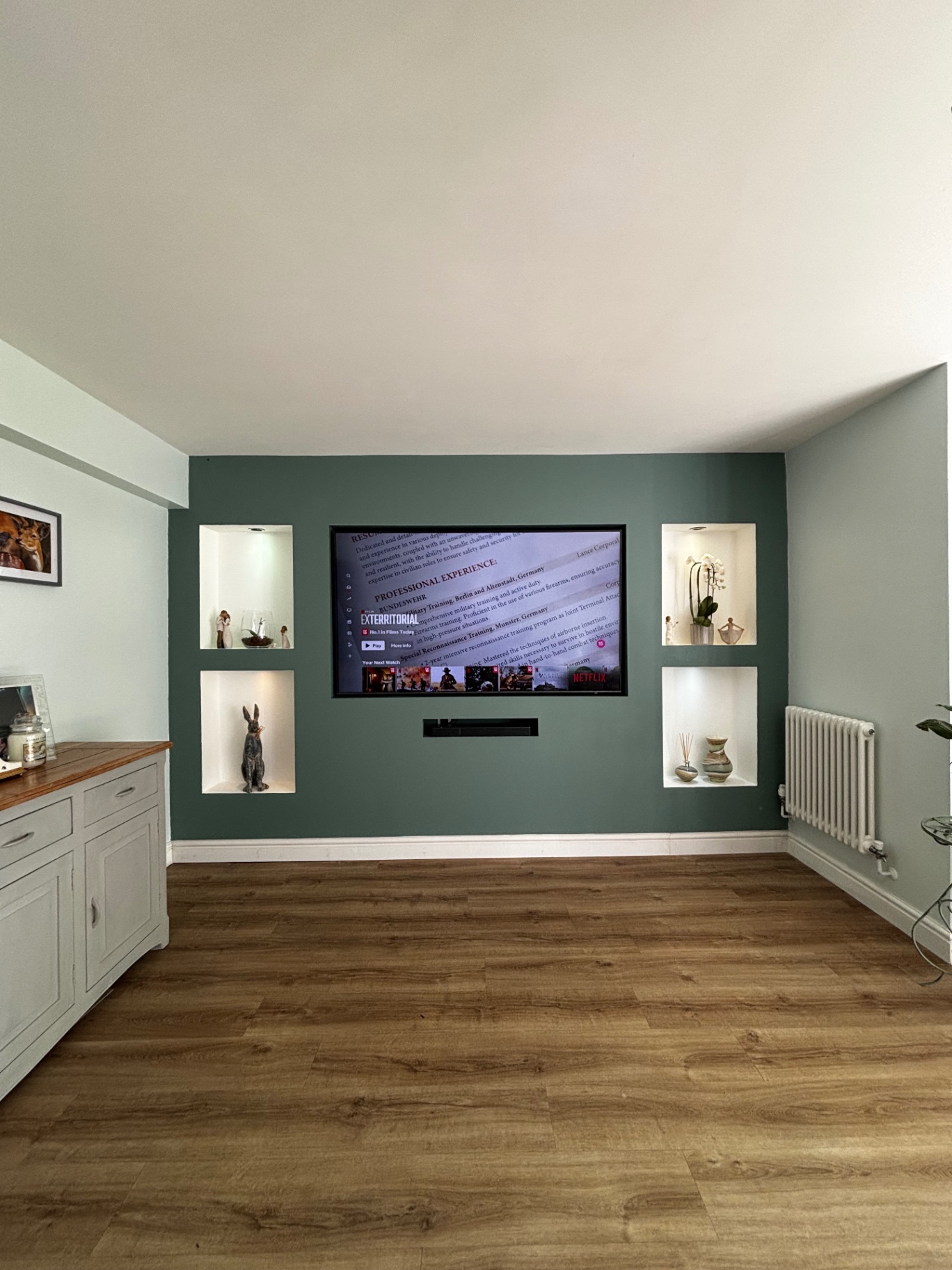 Sage green media wall with inset TV, soundbar slot and four lit display niches