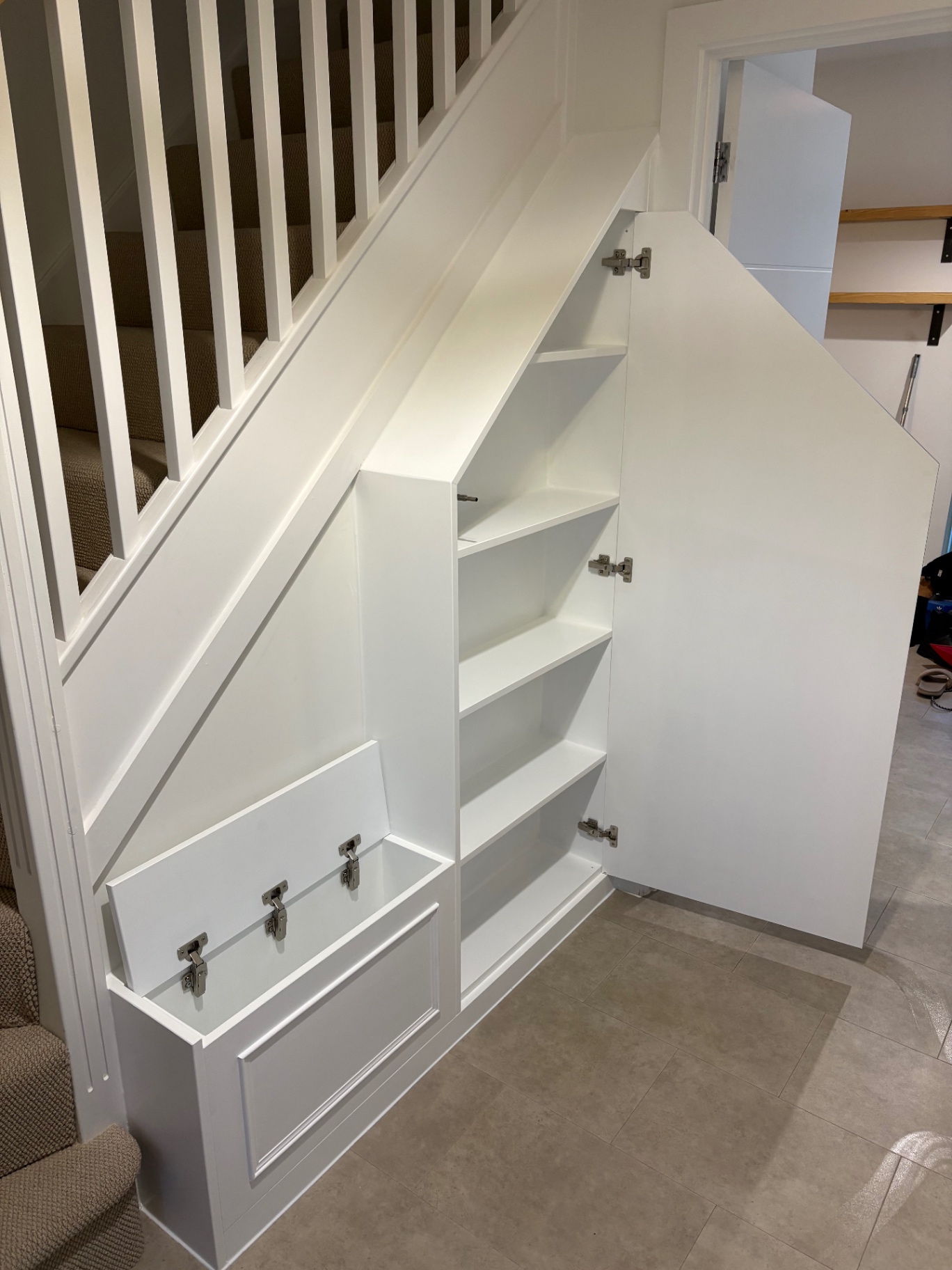 Bespoke understairs storage with shoe drop-front, open shelving and tall cupboard in white