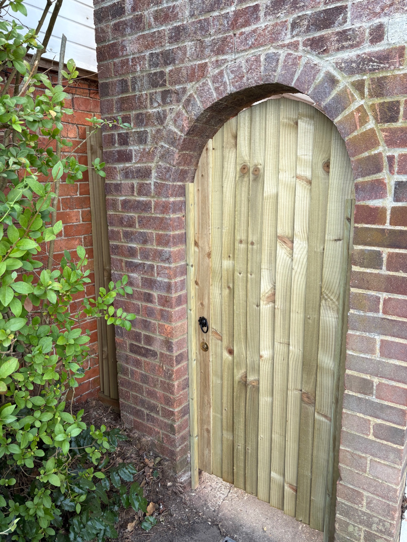 Bespoke arched timber garden gate fitted under a brick archway