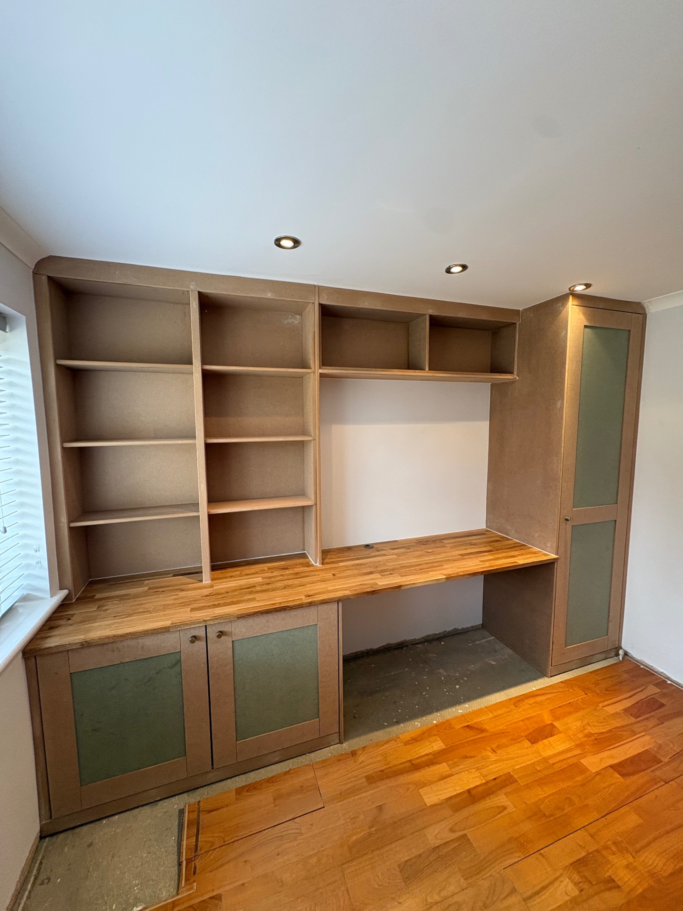 Bespoke fitted study unit with shelving, oak desk and tall cupboard mid-build in raw MDF