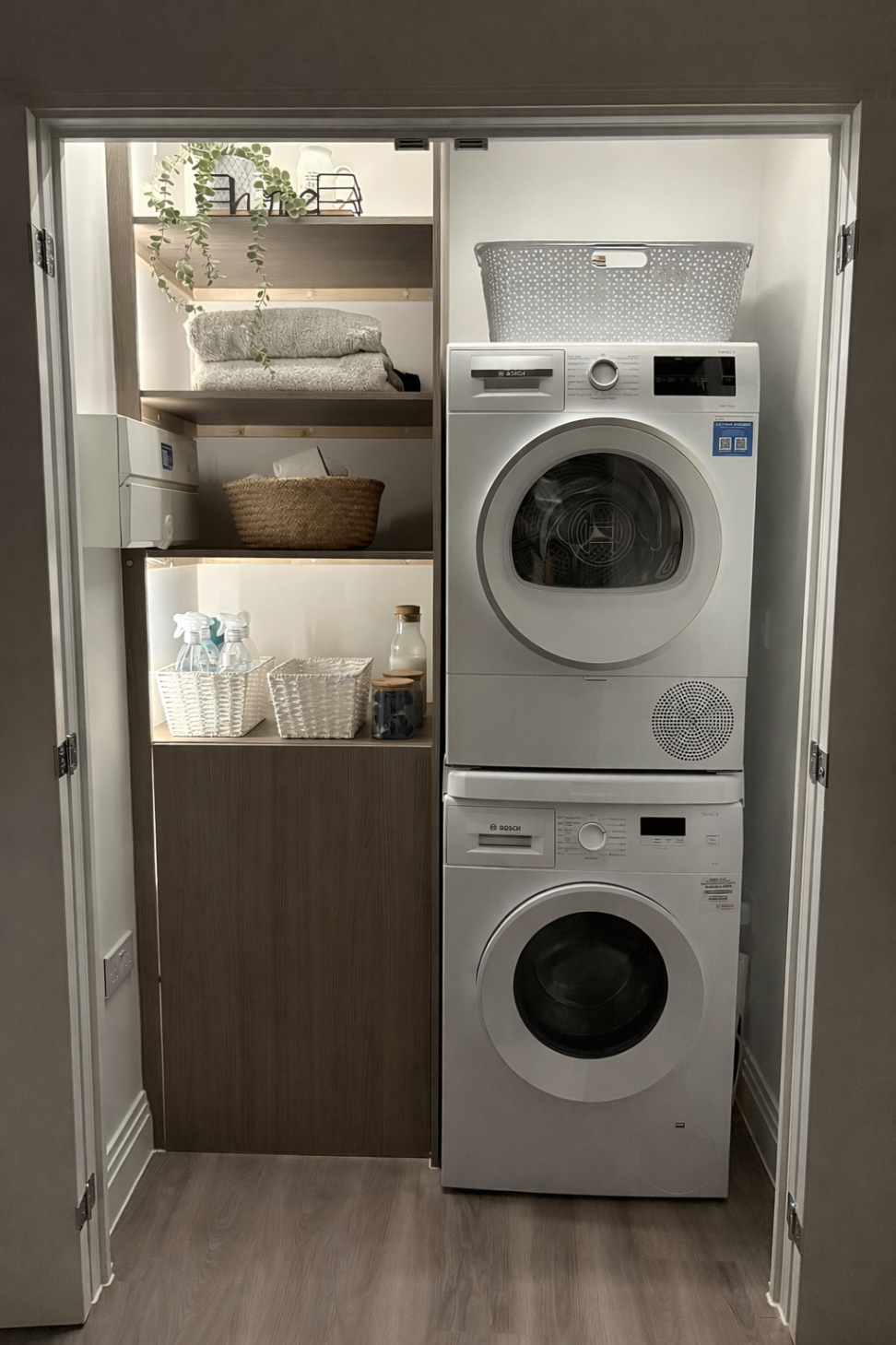 Bespoke utility cupboard with stacked washer-dryer, fitted shelving and storage baskets