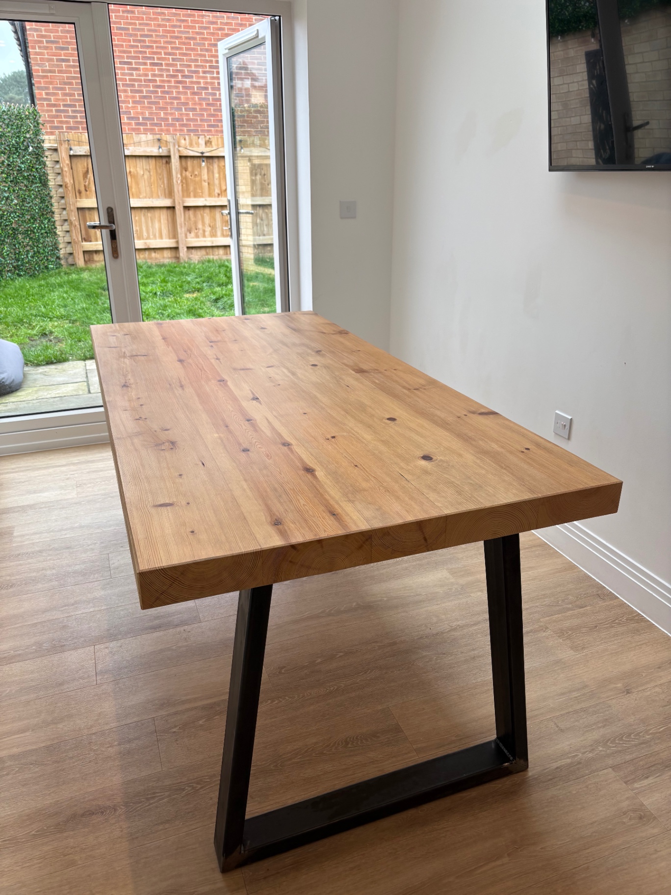 Bespoke reclaimed pine dining table with chunky top and black steel trapezium legs