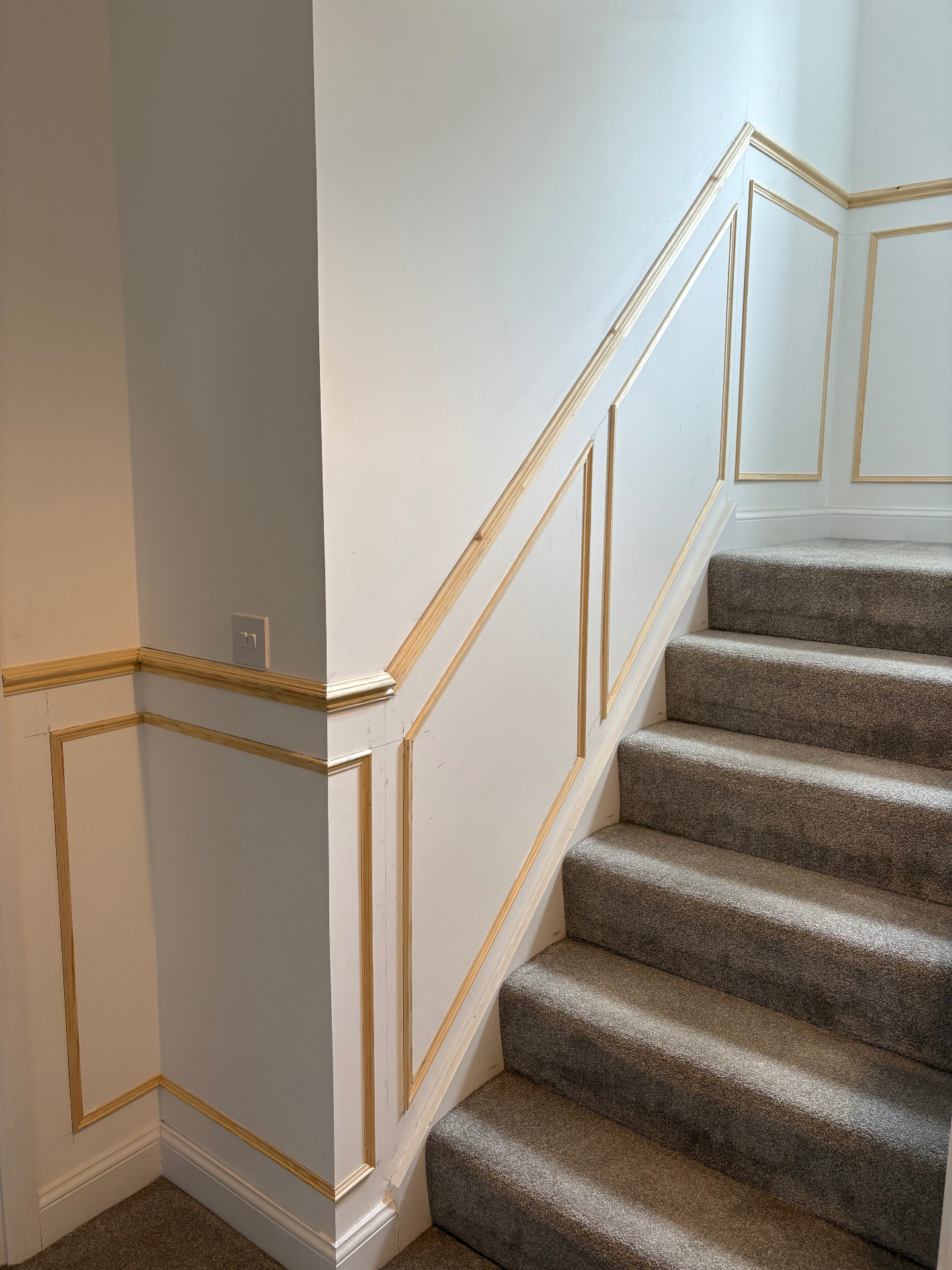 Staircase shaker panelling with natural wood trim and carpet runner