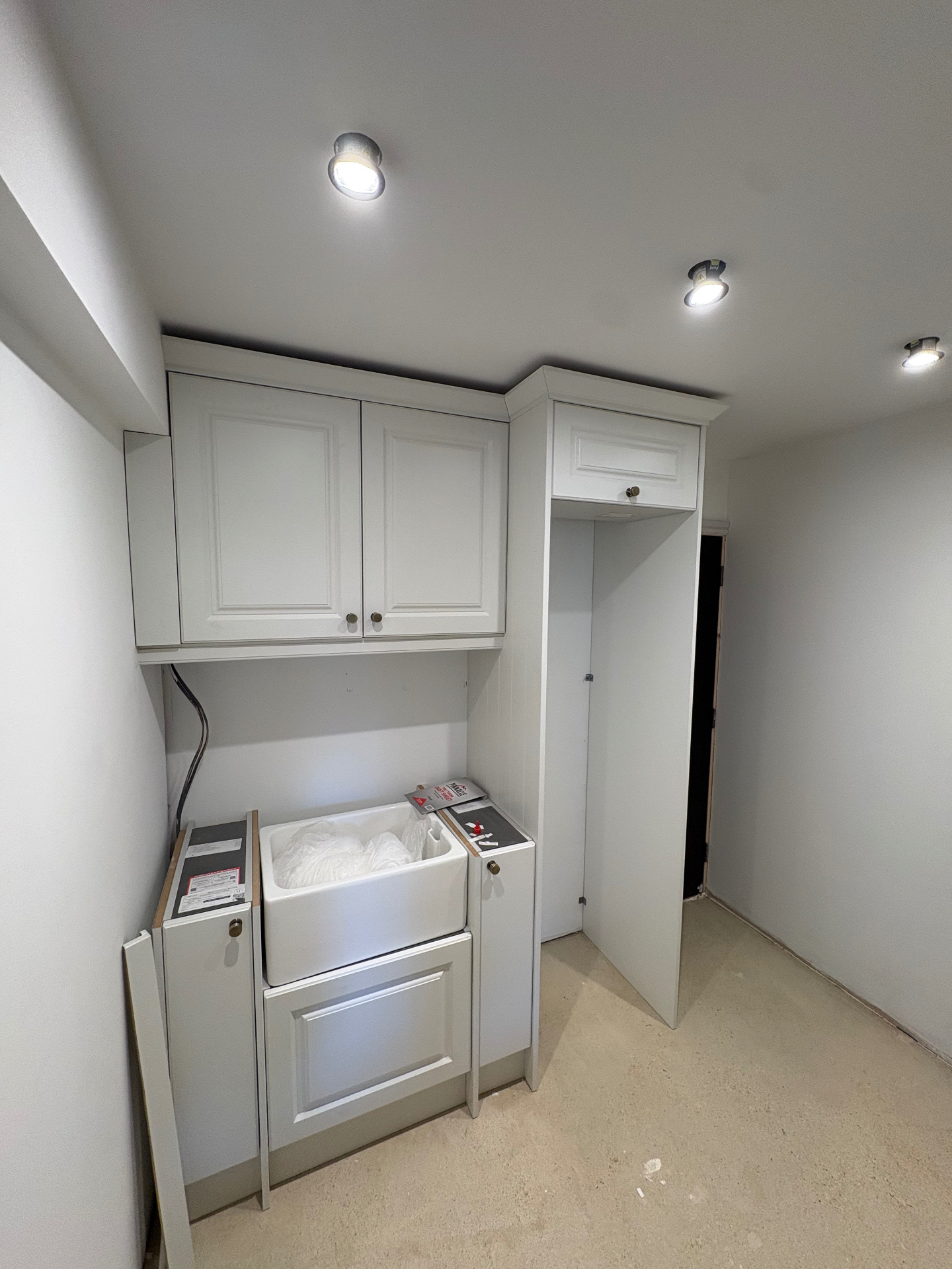 Utility room with belfast sink and fitted shaker cabinets mid-install