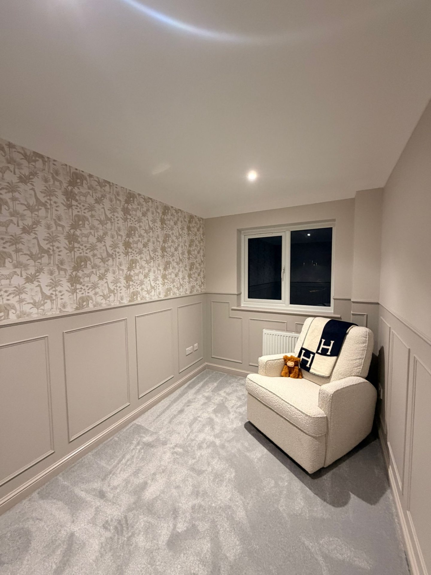 Taupe nursery wall panelling with feature wallpaper and soft grey carpet