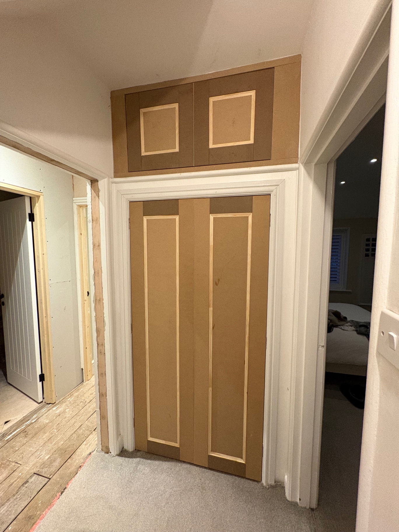 Bespoke overdoor storage cupboards and matching panelled door in raw MDF