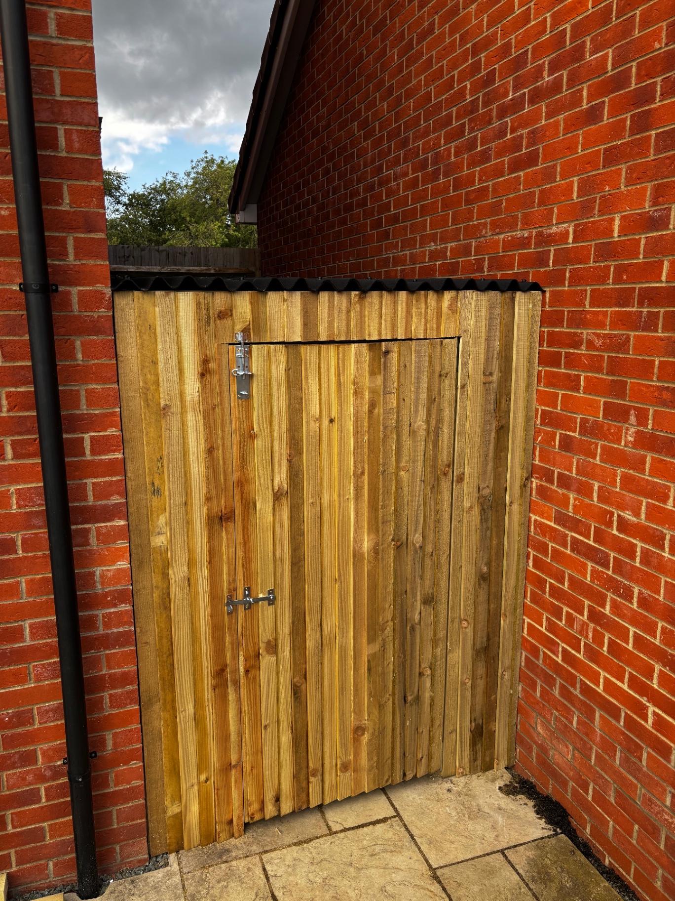 Bespoke timber bin store with framed access hatch and corrugated black roof