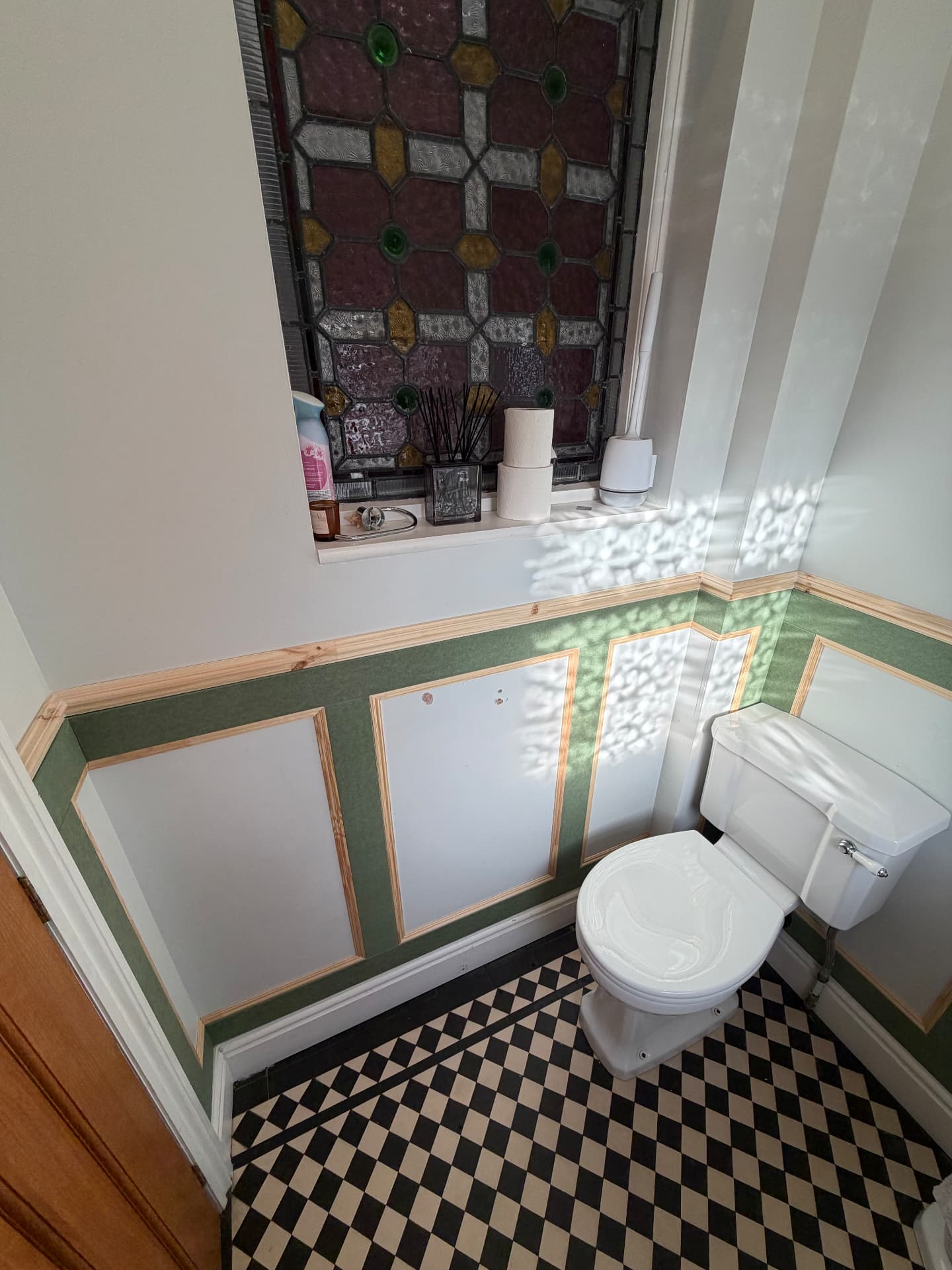 Three picture-frame panels fitted along a cloakroom wall beneath a leaded stained-glass window