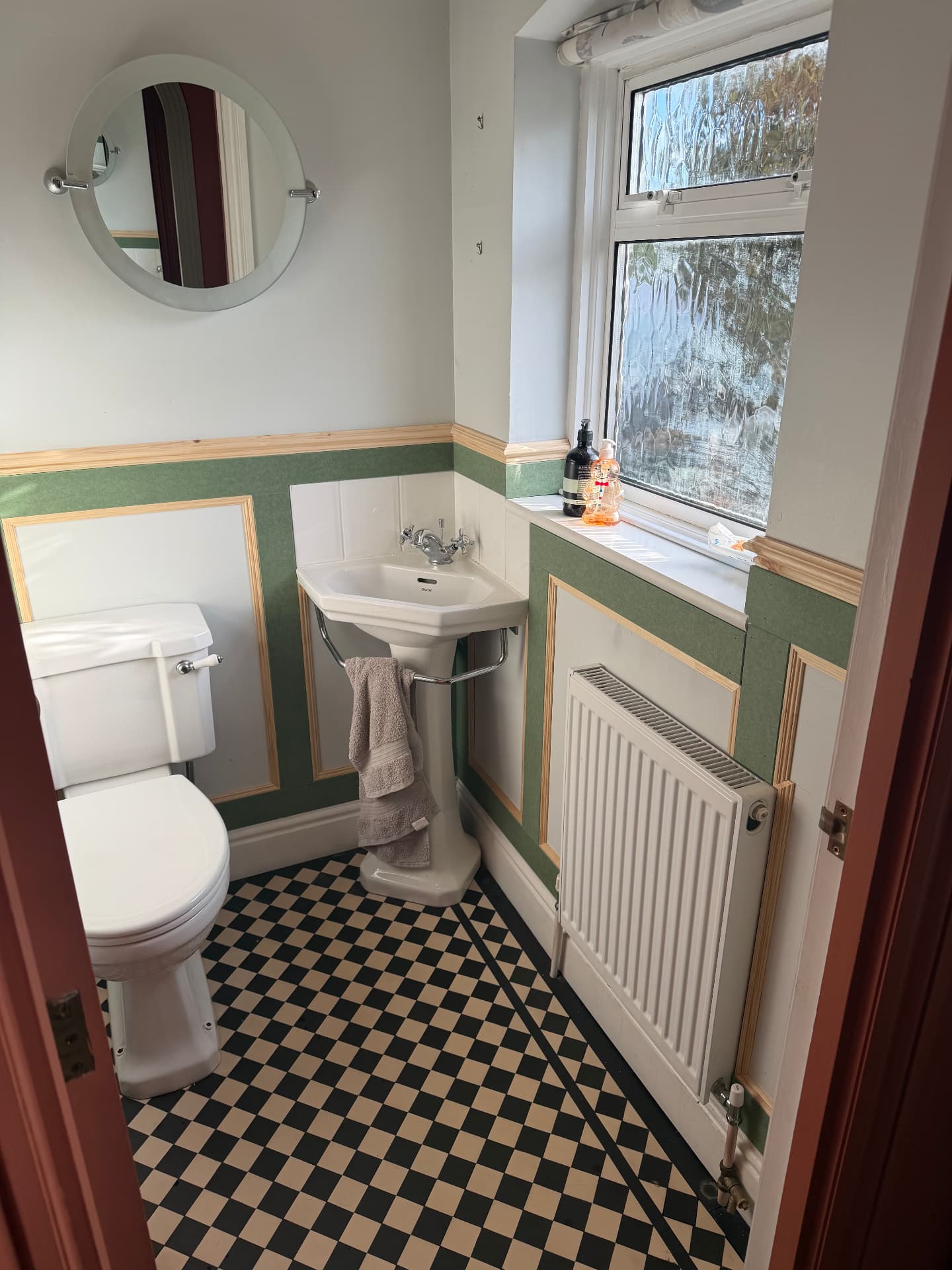 Half-height picture-frame panelling in progress in a cloakroom, fitted around the corner basin and radiator