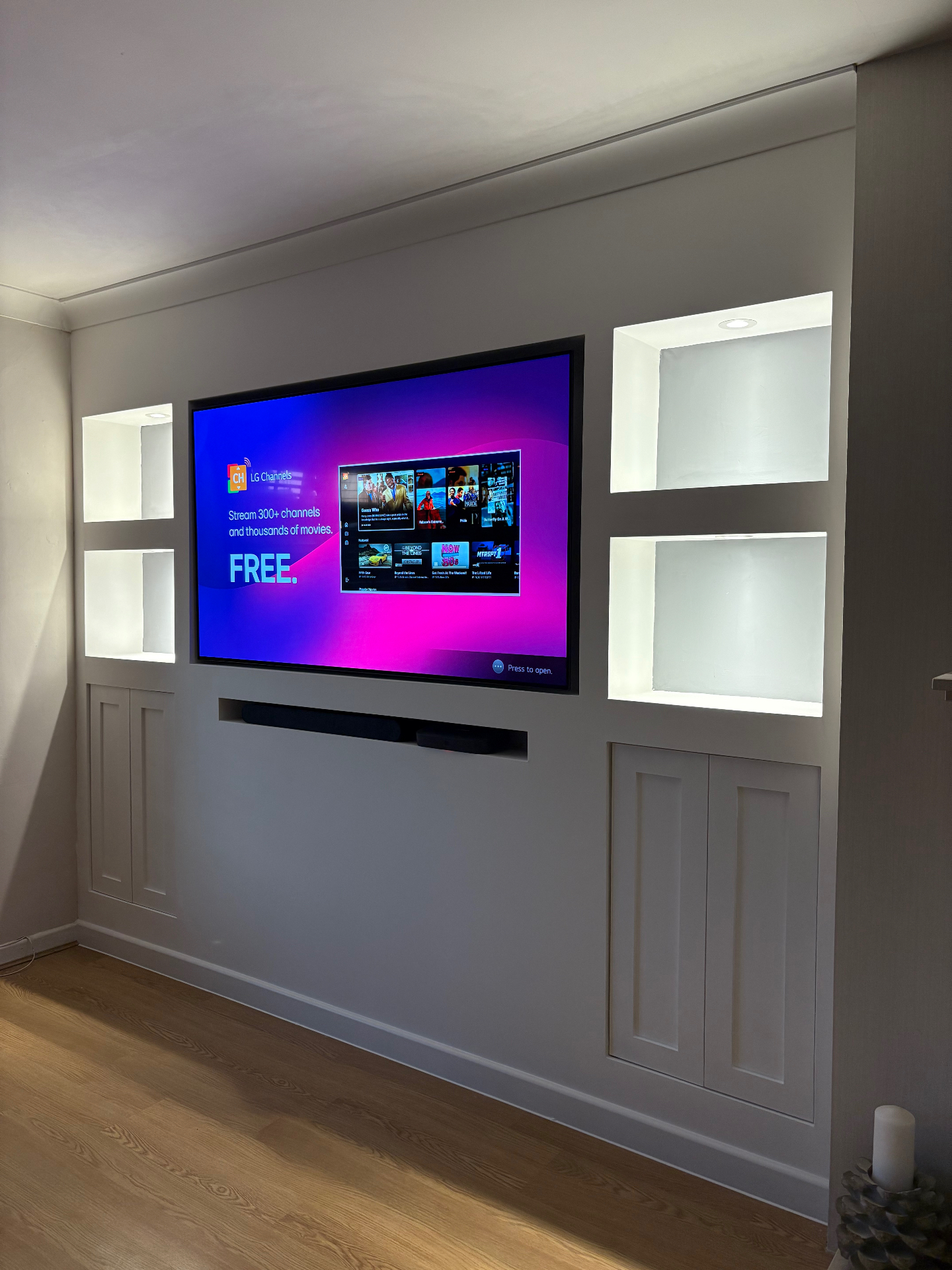 Grey media wall with framed TV, lit display niches and shaker base cupboards