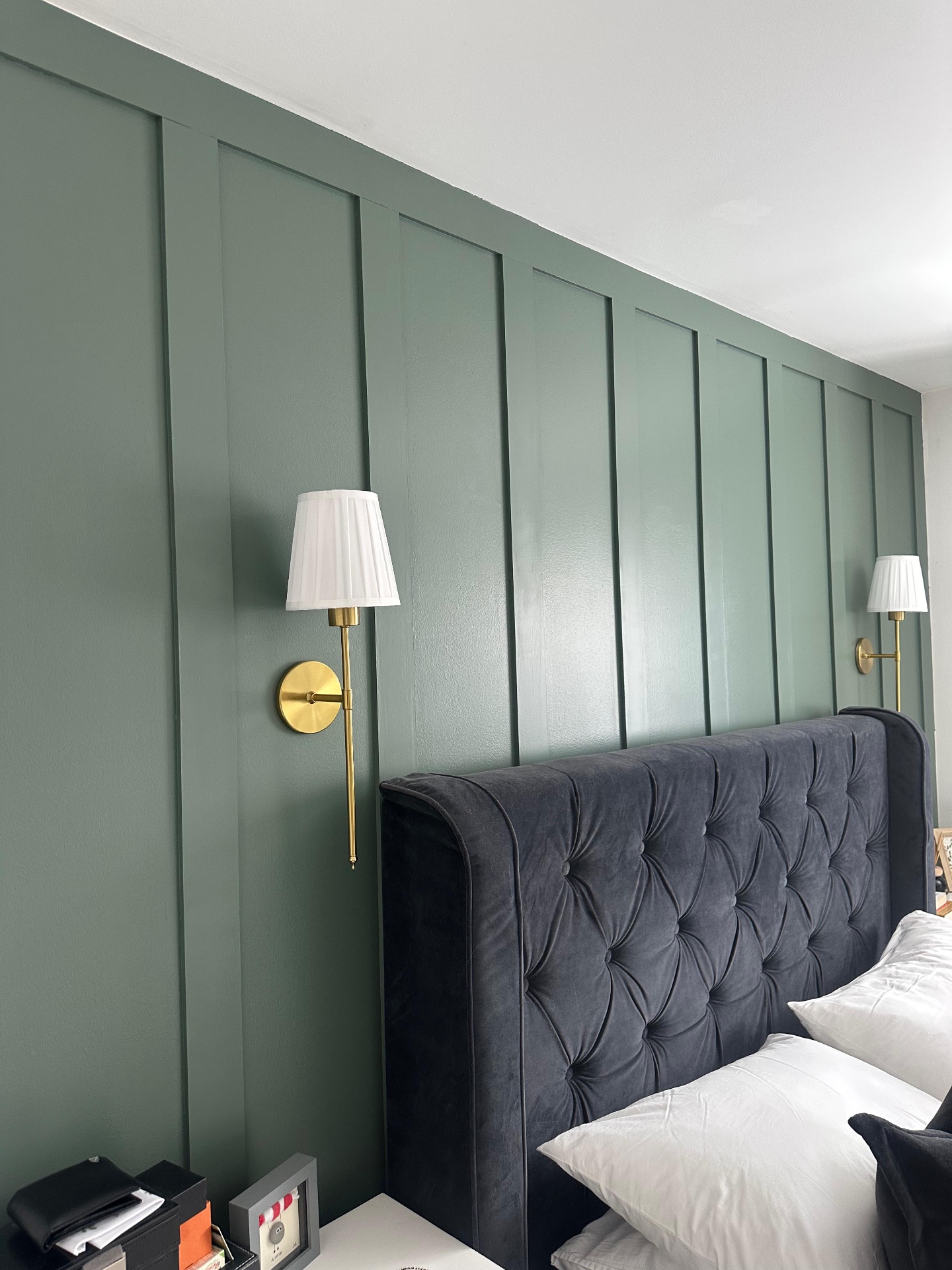 Full-height sage bedroom wall panelling with brass bedside lights