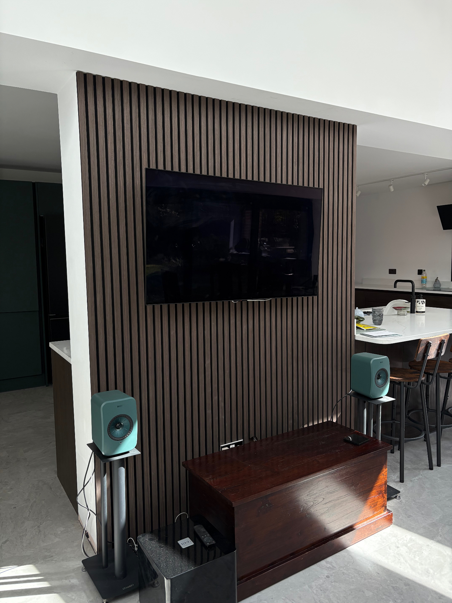 Contemporary slatted media wall with wall-mounted TV in an open-plan space